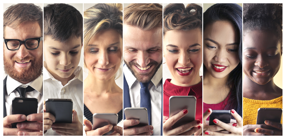 The image is showing seven people looking down at a mobile phone in their hands.